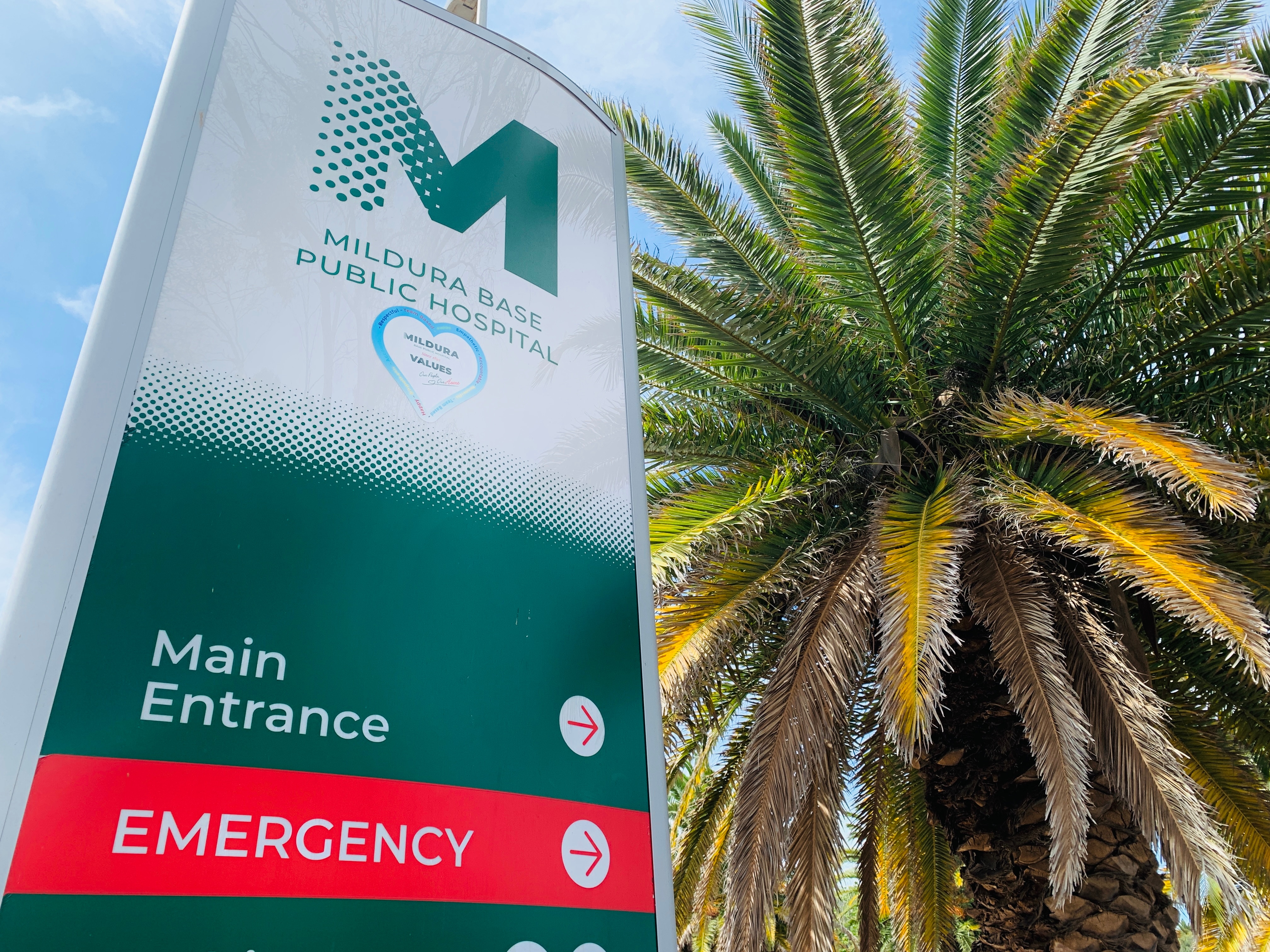 A sign reads 'Mildura Base Public Hospital', beside a palm tree.
