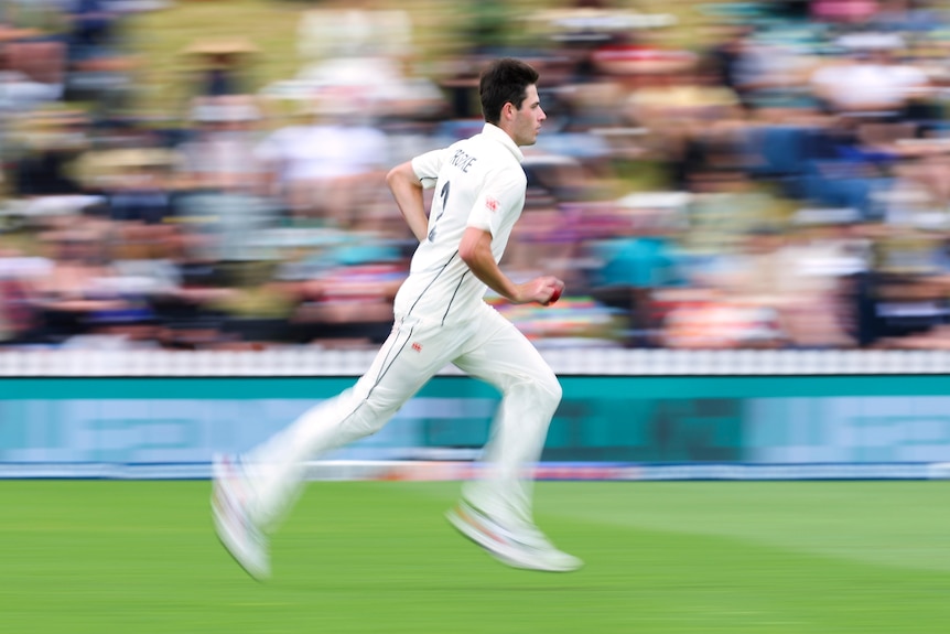 A male cricketer wearing whites runs.
