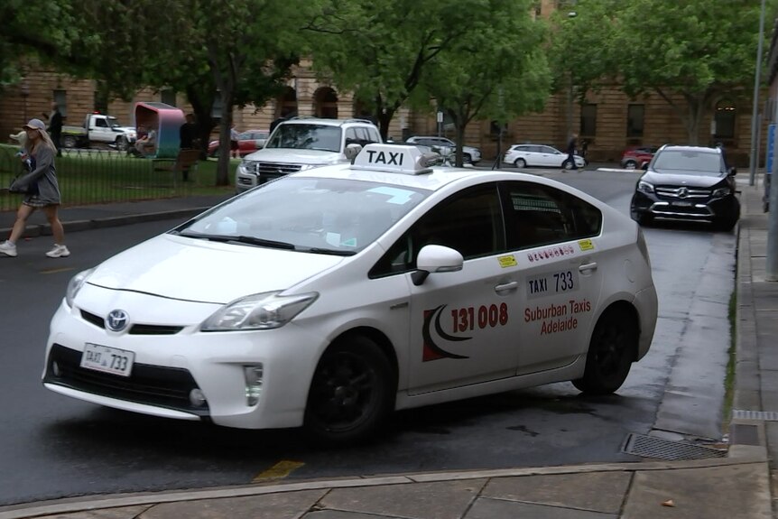A Toyota Prius taxi on a wet city street