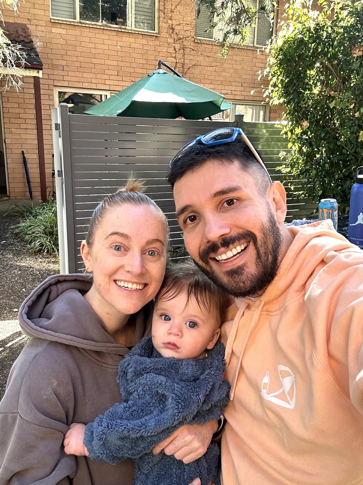 A man and woman holding a baby smile camera