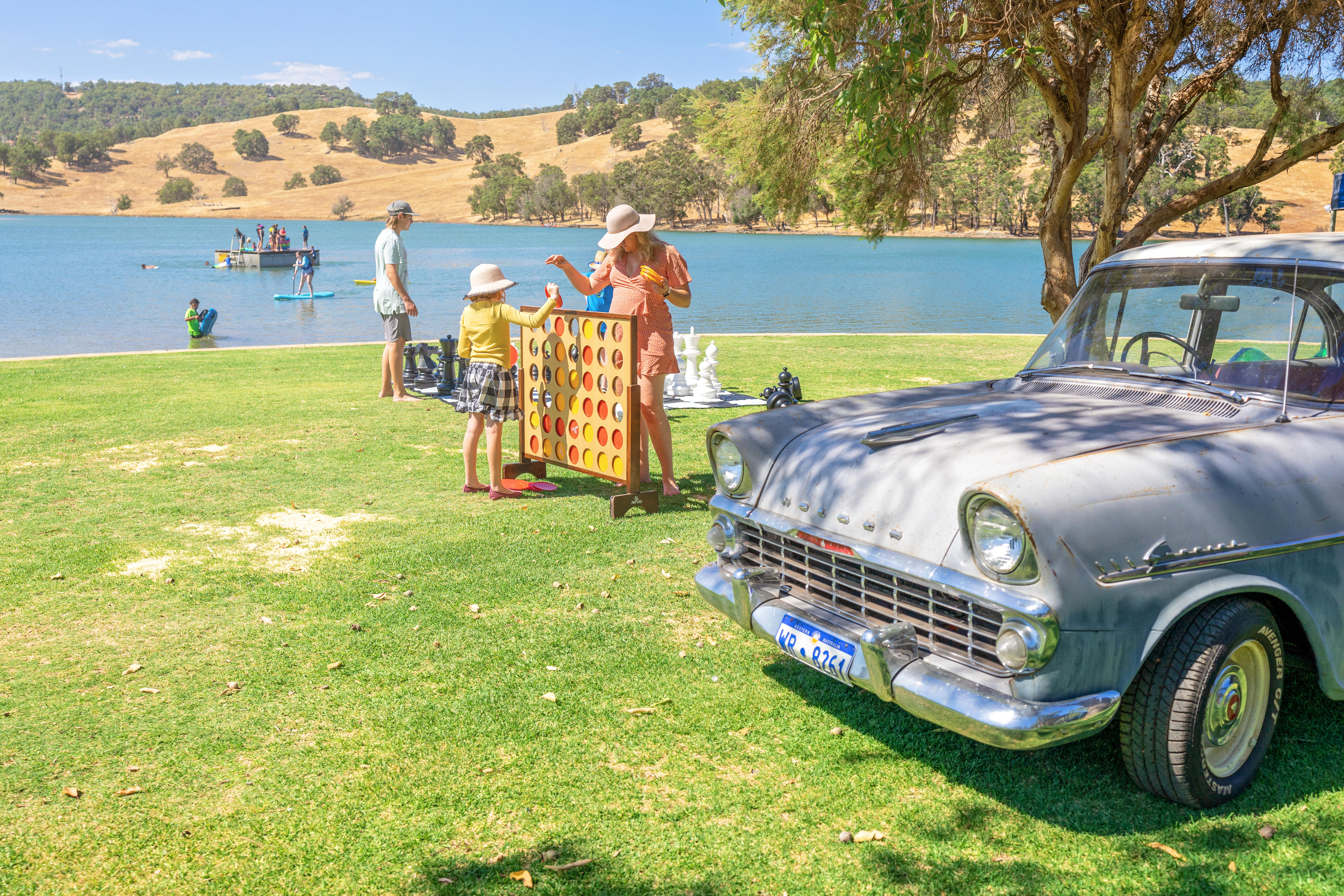 woman and child stand in middle of photo with a car to the right. 