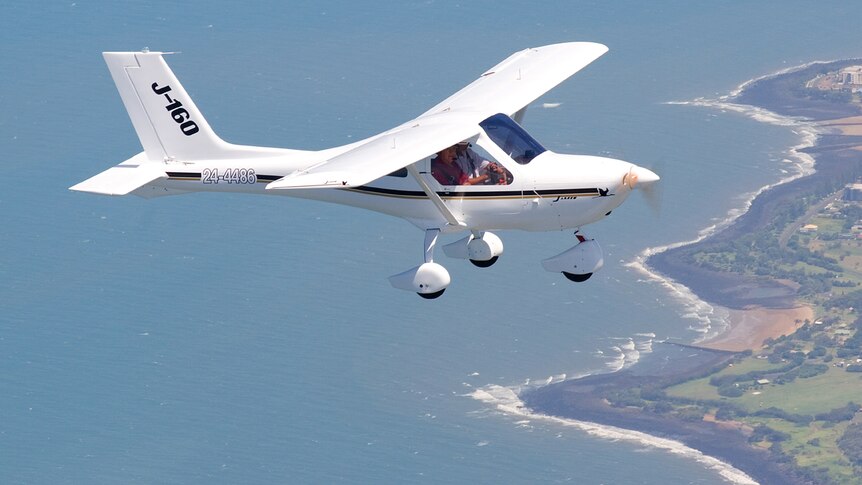 A Jabiru recreational aircraft flies over the ocean