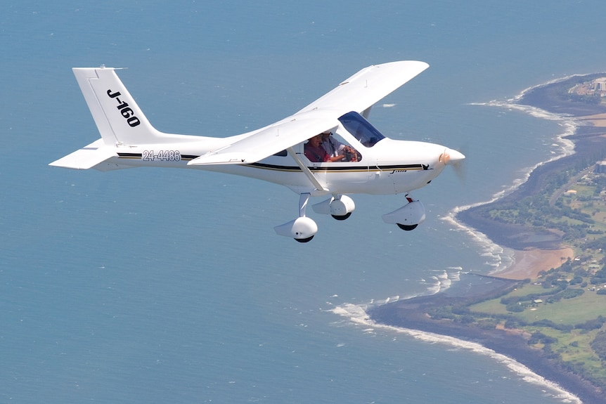 A Jabiru recreational aircraft flies over the ocean