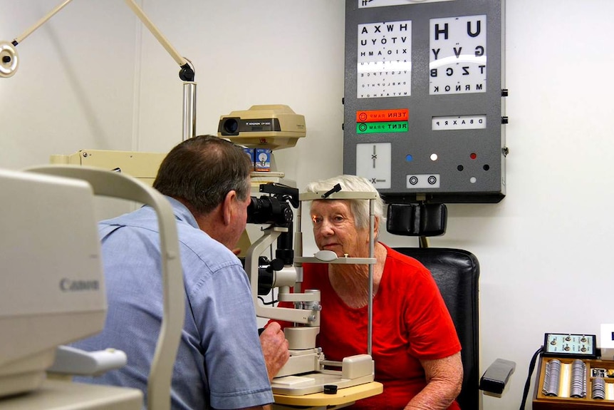 A lady in a red shirt having her eyes examined