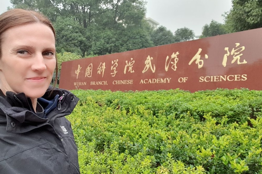 A woman stands next to a sign that reads 'Wuhan Branch, Chinese Academy of Sciences'