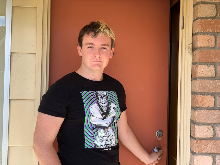 A young man opens a door to a house