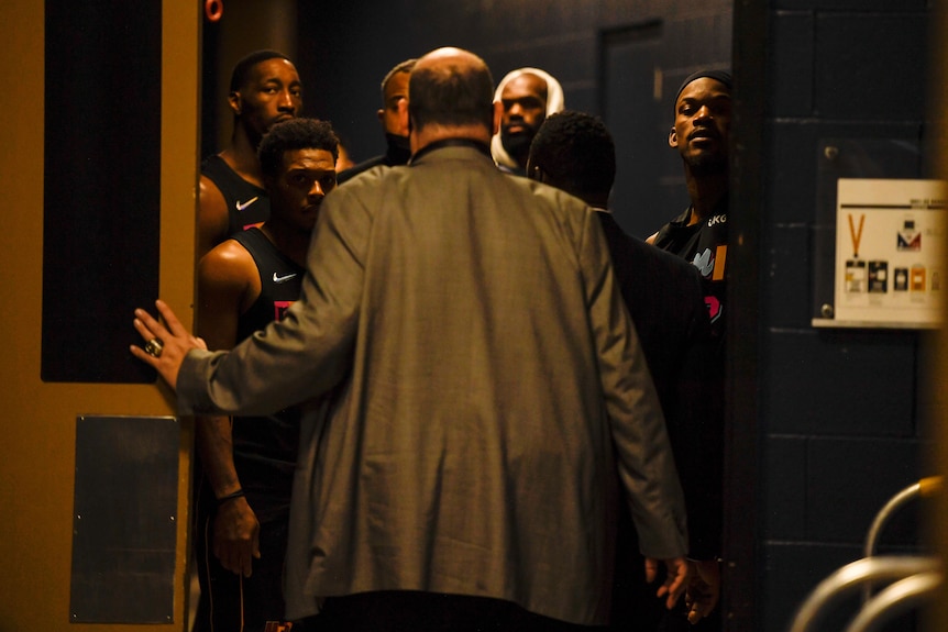 A group of angry NBA players wait in a doorway for their opponents after a game.