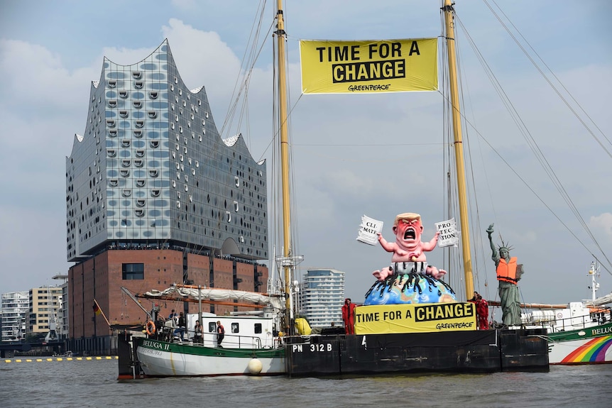 Greenpeace activists stay next to the giant statue depicting US President Donald Trump.