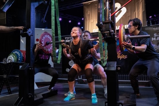A young woman lifts weights and was discovered by three men