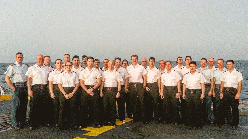 Naval officers in short-sleeved shirts on the deck of a ship.