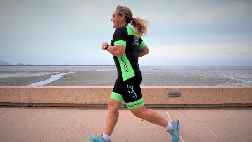 50-year-old woman in black and lime green lycra runs along the Cairns Esplanade.
