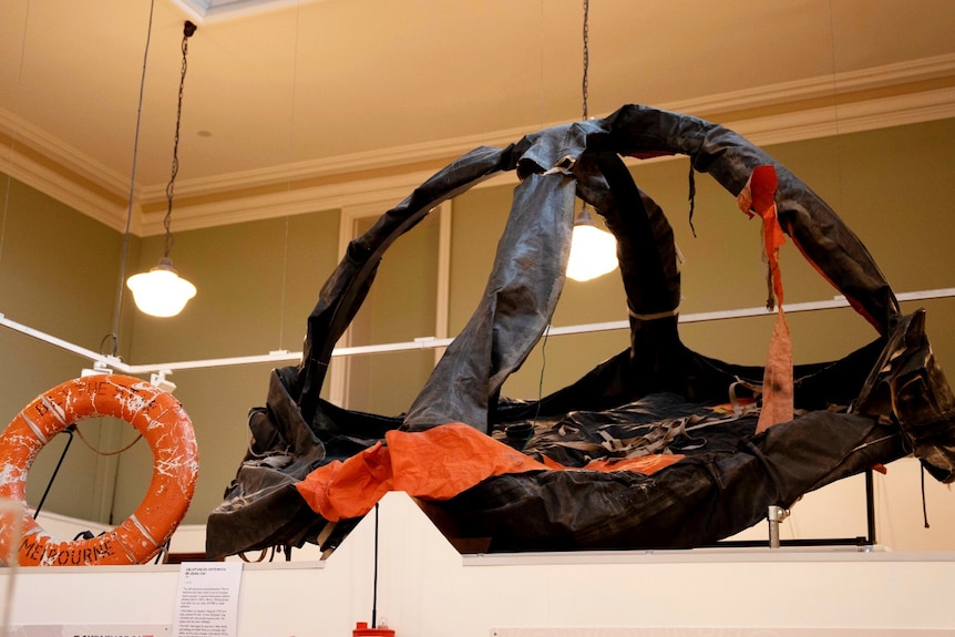 A blue and orange deflated life raft suspended in a museum roof