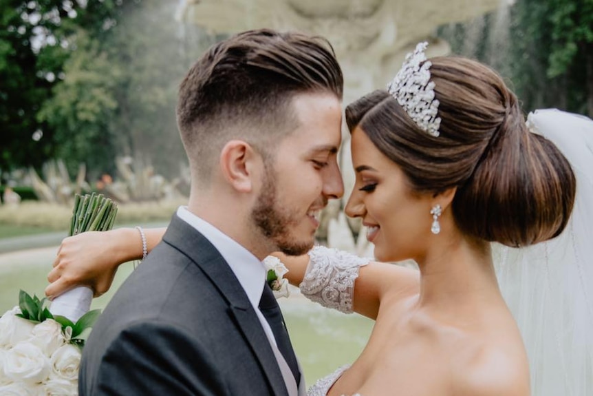 Lindita and Veton Musai, dressed in wedding attire in a portrait-style photograph.