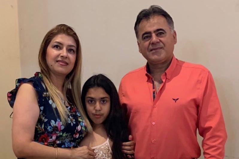 Arsalan Sadeghi Iveli stands next to his wife and daughter.