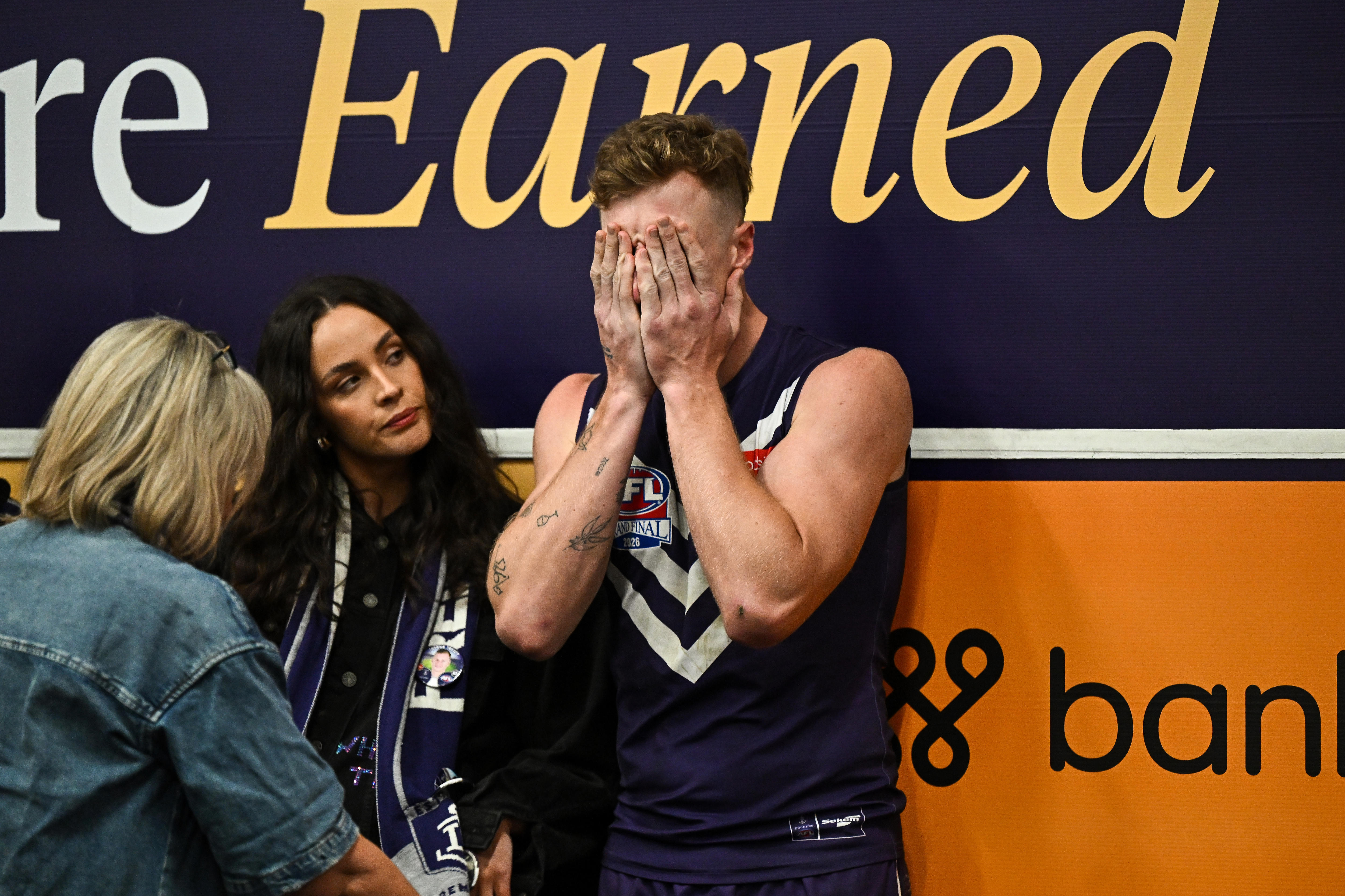 Josh Treacy covers his face with both hands and is comforted
