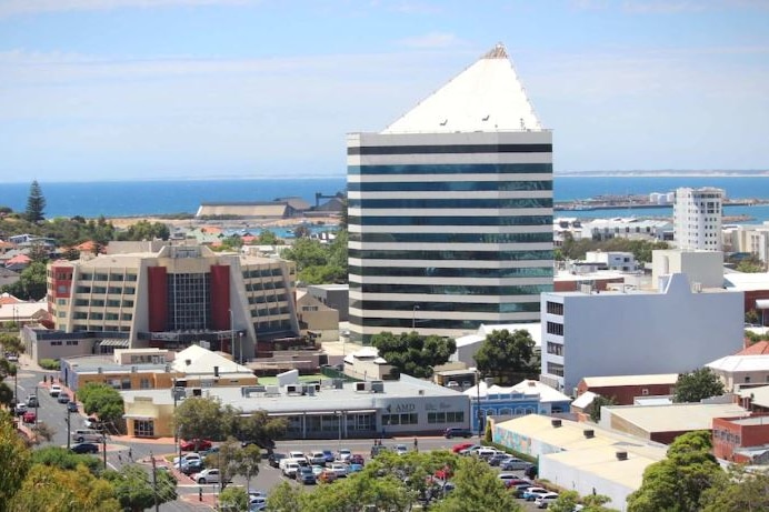 A wide shot showing three skyscrapers with blue water in the background.