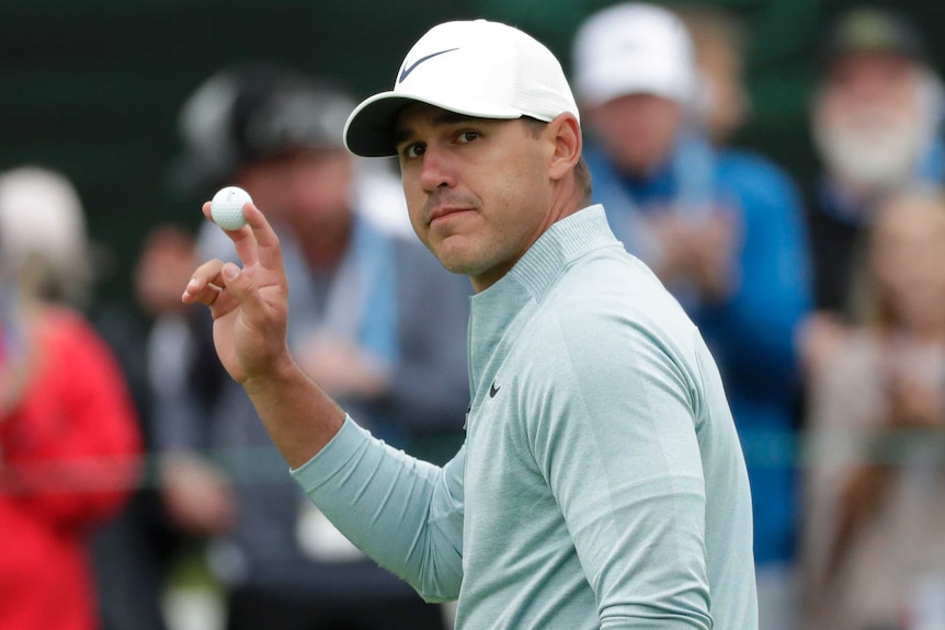 Brooks Koepka holds up his ball