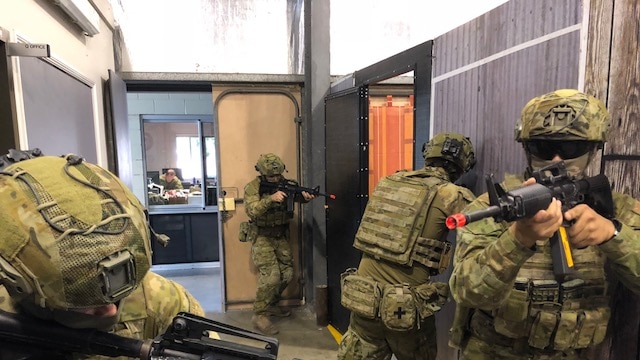 Soldiers with weapons go through a building