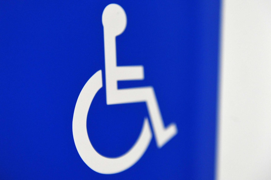A white and blue disability sign on a door representing a person in a wheelchair.