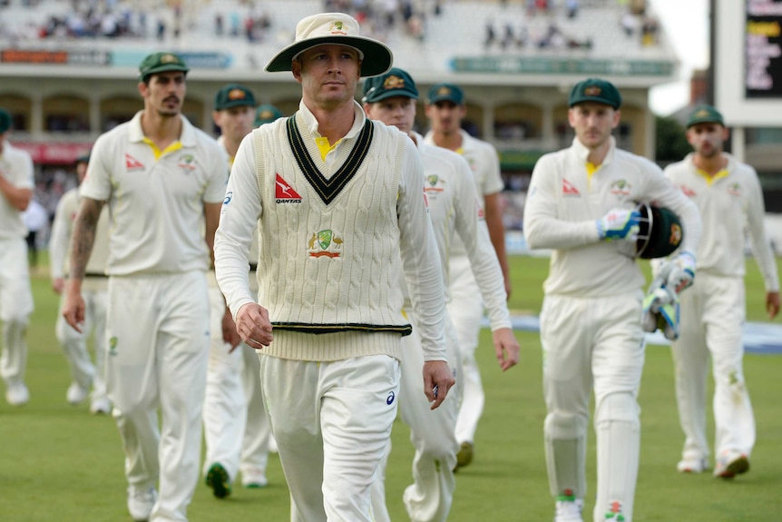 Michael Clarke walks across the field, followed by his teammates.