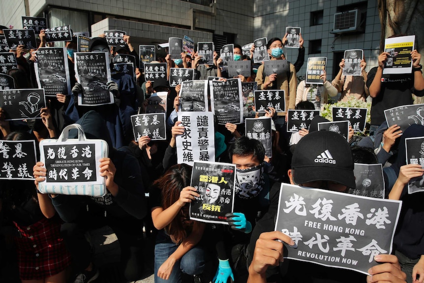 Dozens of Hong Kong protesters wear black and hold up signs