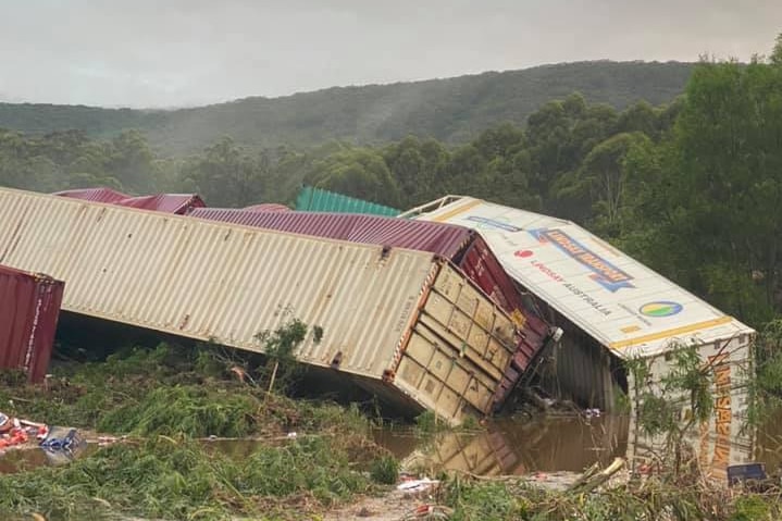 Four containers battered and bent in a flooded paddock