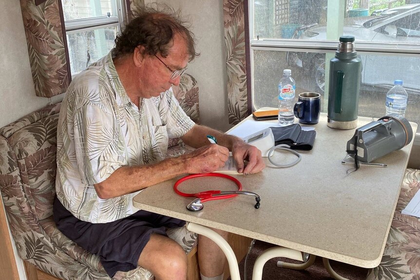 Dr Lee takes notes in caravan for his patients