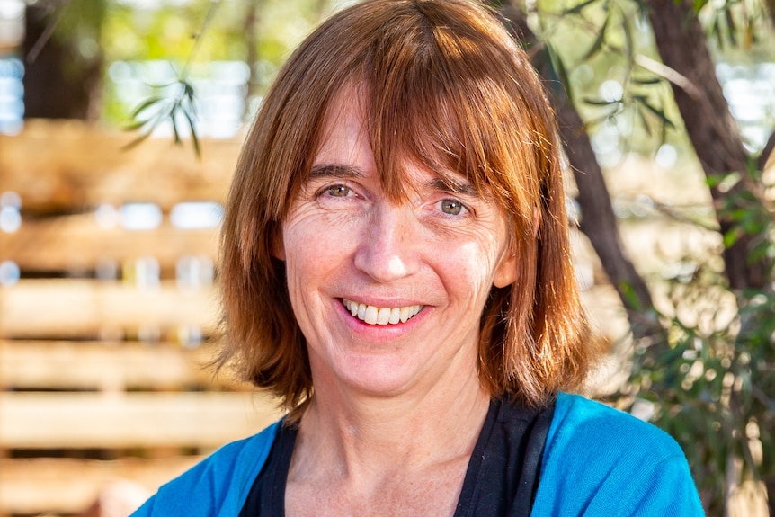 A middle aged woman with red hair smiling.