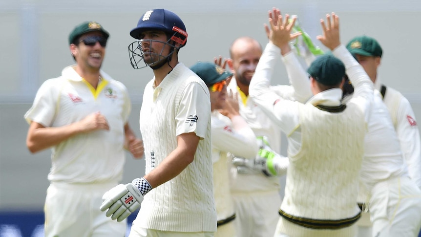 Alastair Cook leaving the field as Australian players celebrate in the background.