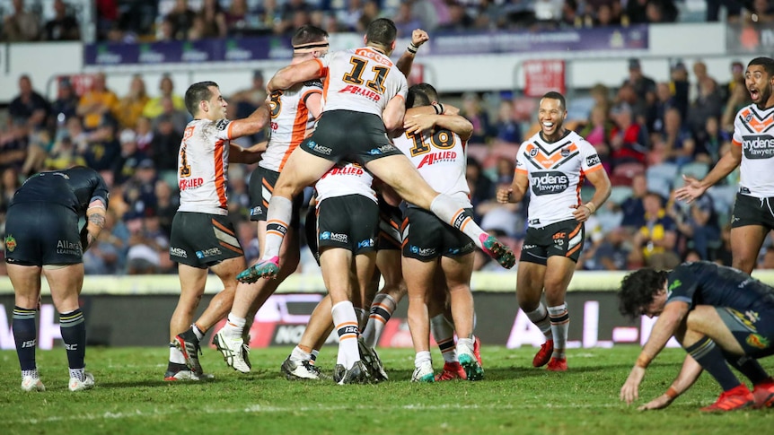 NRL players jump on top of each other in celebration at a victory.