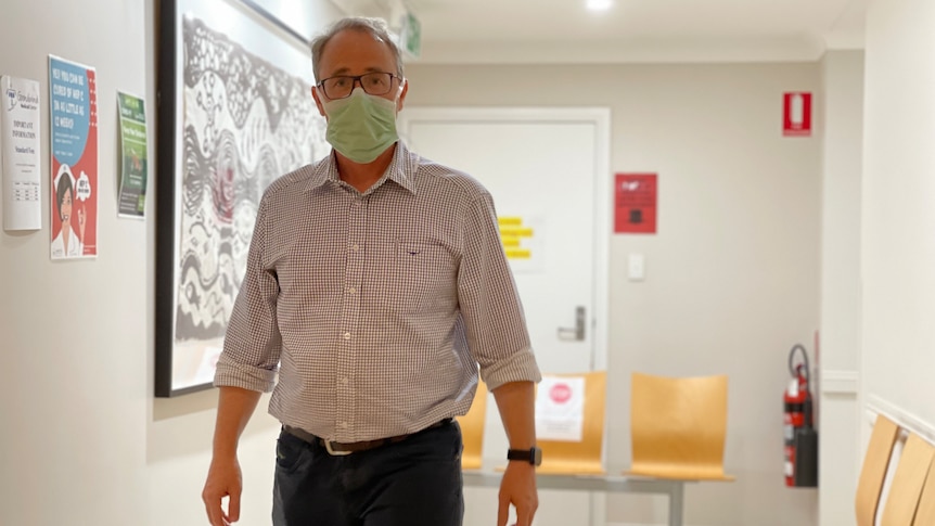 Dr Matt Masel walks down the hallway of his surgery wearing a mask. 