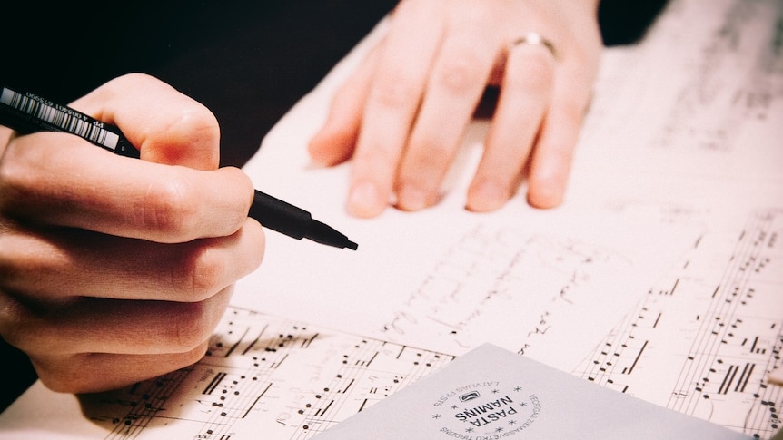 A pair of hands writing music.