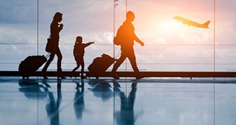 A family of three walk through an airport as a plane takes off.