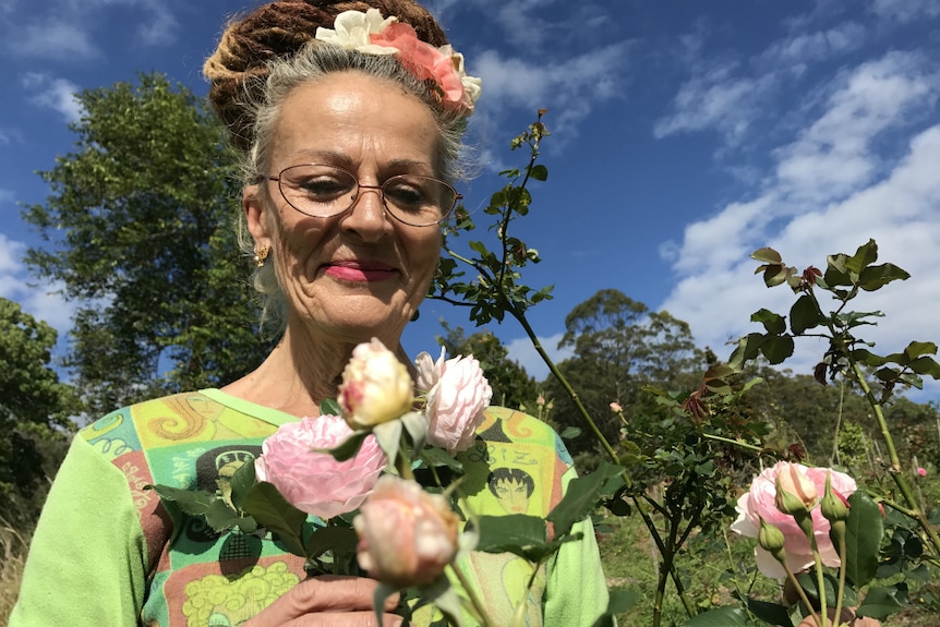 Caz Owens smiles down at a blossoming rose bush
