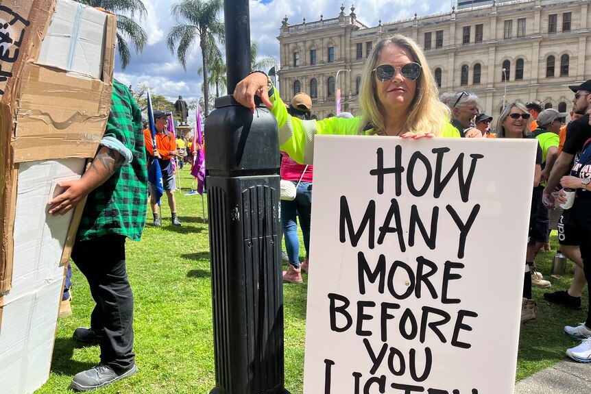 woman holding a sign in font of parliament
