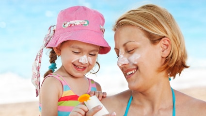 A woman and her daughter applying sunscreen