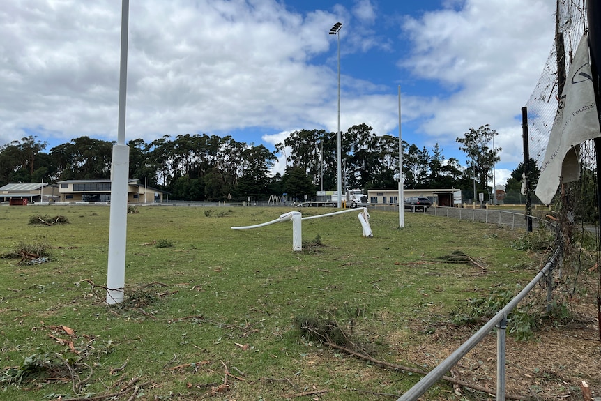 Two goal posts are bent over while tree branches litter the ground at the Mirboo North Football Club.