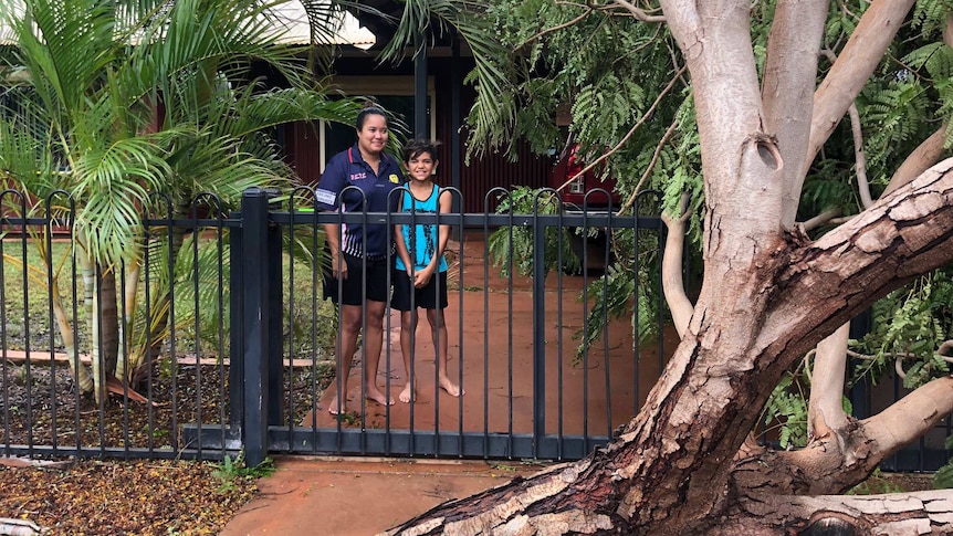 A woman and her young son in the driveway of their house which is blocked by a fallen tree.