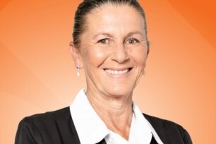 A smiling woman against an orange background.