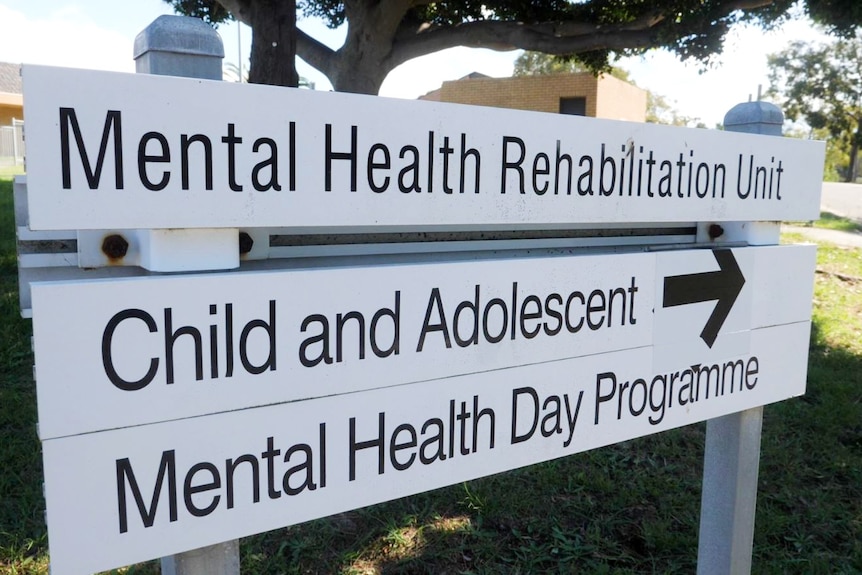White, wooden signage pointing way to the Mental Health Rehabilitation Unit, Child and Adolescent and Mental Health Day Programs
