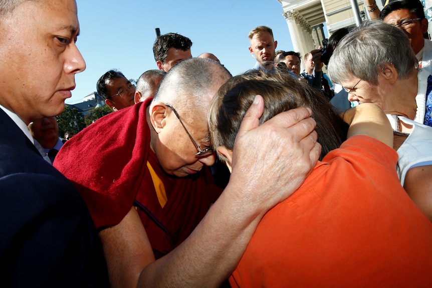 一位僧人抱着一位孩童的头