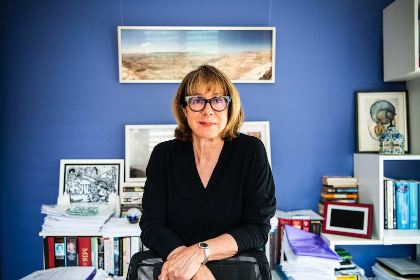 A woman in a black shirt with a blue wall as background