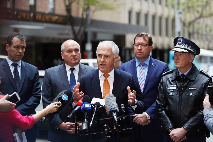 Malcolm Turnbull fronts a group of important looking people at a press conference.