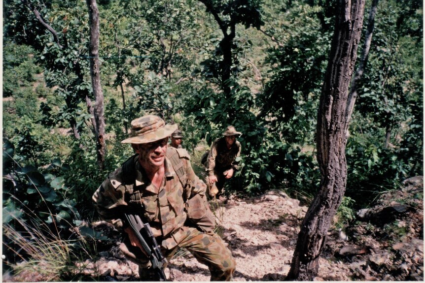 A film photograph of people in the army in a jungle.