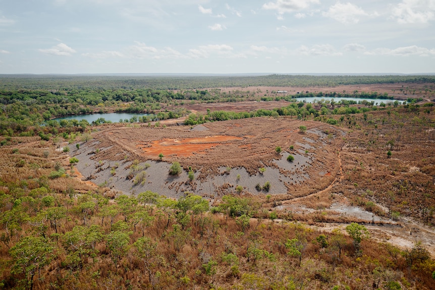 A mining site surrounded by trees is seen from above. 
