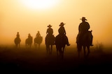 Six people ride on horses in the mist