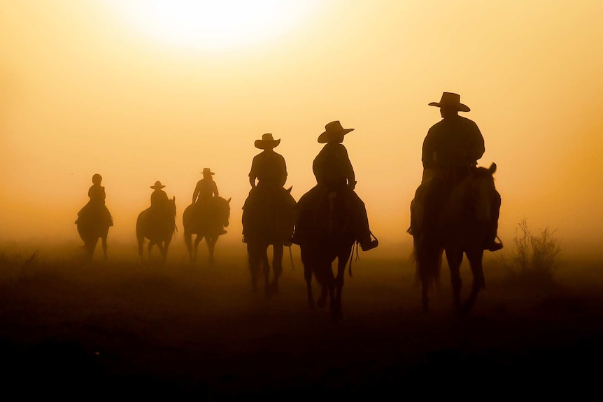 Six people ride on horses in the mist