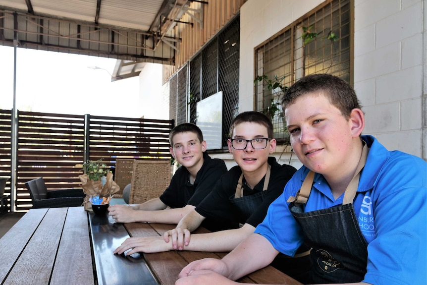 Three young men sit at a table