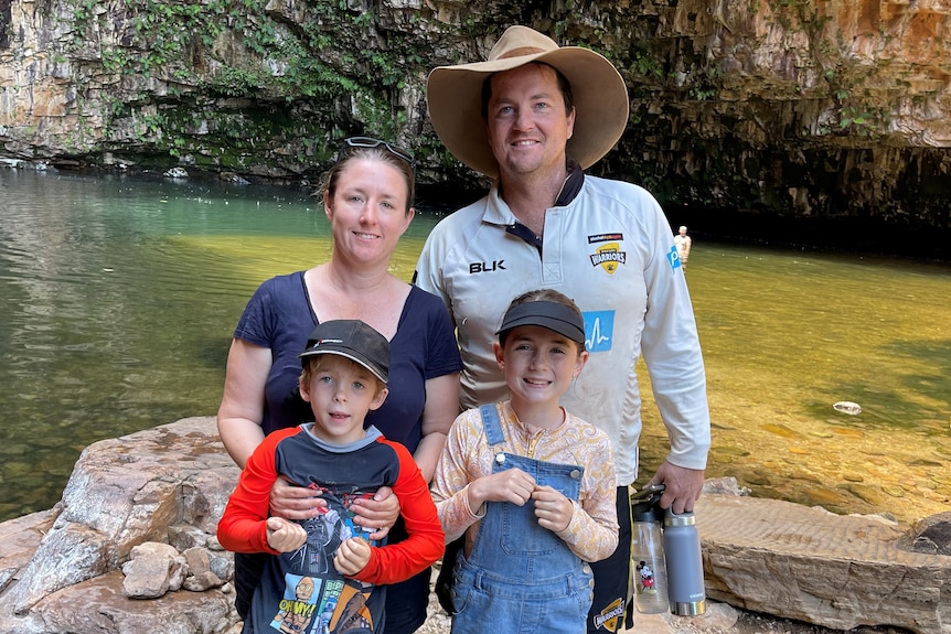 a family of four in front of a waterfall pool