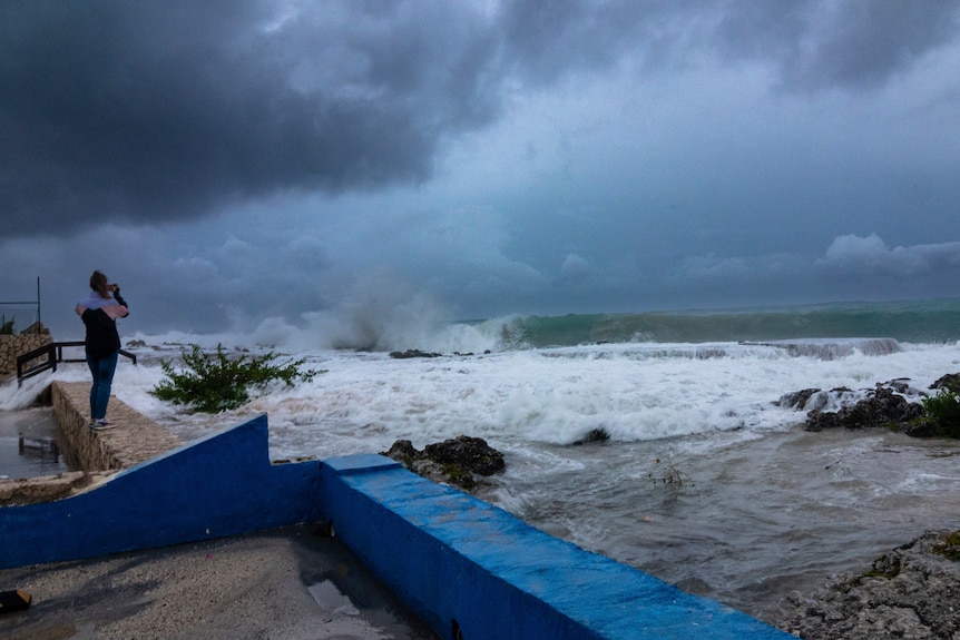 Una donna osserva le onde che si infrangono. 